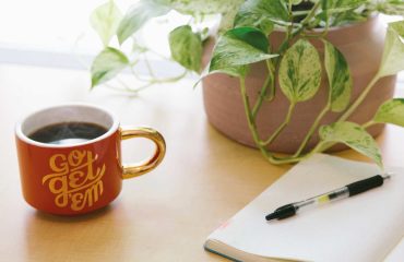 Notepad-and-Coffee with a plant on a table