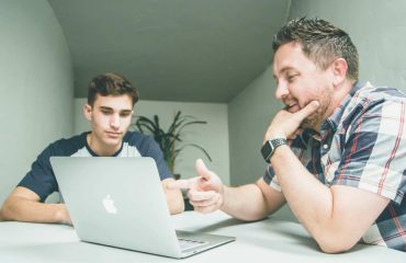 Two colleagues talking over their laptop