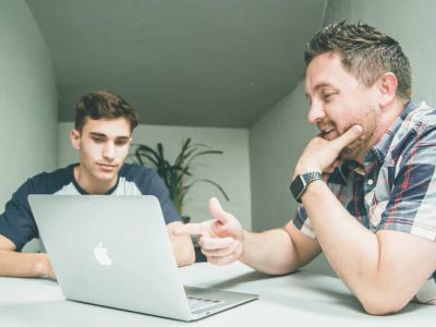 Two colleagues talking over their laptop