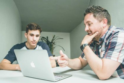 Two colleagues talking over their laptop