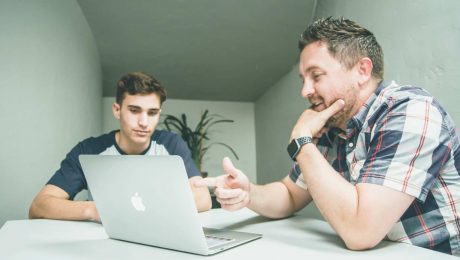 Two colleagues talking over their laptop