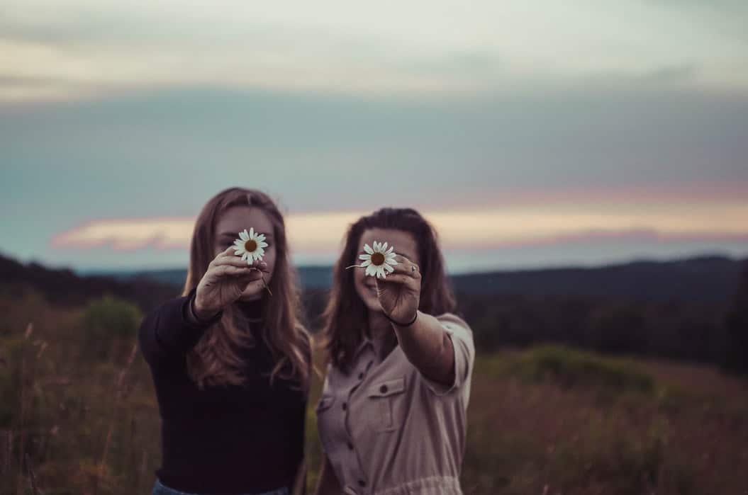 Two ladies in a field holding flowers