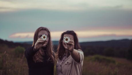 Two ladies in a field holding flowers