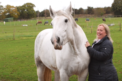 Lady pictured smiling with her horse on a field