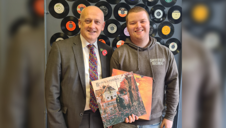 Vinyl music shop owner in front of decorative vinyl's on the wall