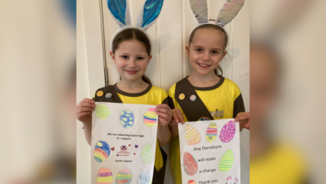 Two young girls showing their posters wearing their brownies uniform