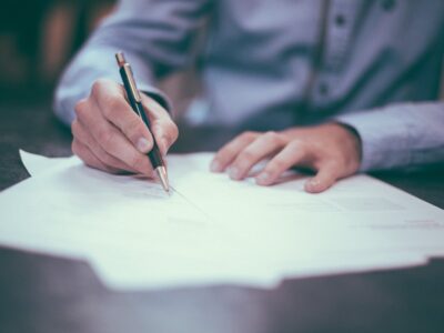 Gentleman writing on a piece of paper, wearing a blue shirt