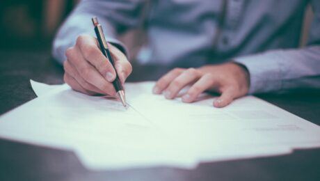 Gentleman writing on a piece of paper, wearing a blue shirt