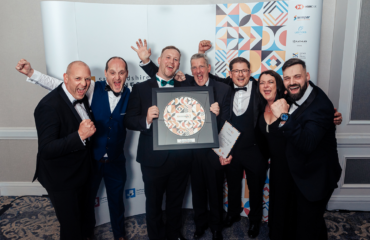 Wiltshee's Team holding their Awards at Staffordshire Chambers' Business Awards standing in front of the graphic wall