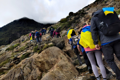 A group of people climbing up a hill with a lot of rocks and steps on the way to the top.