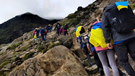 A group of people climbing up a hill with a lot of rocks and steps on the way to the top.