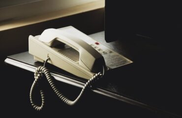 Telephone on top of a black desk by a laptop