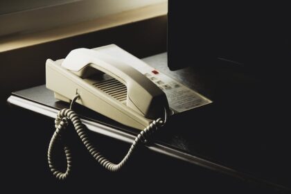 Telephone on top of a black desk by a laptop