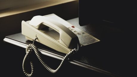 Telephone on top of a black desk by a laptop