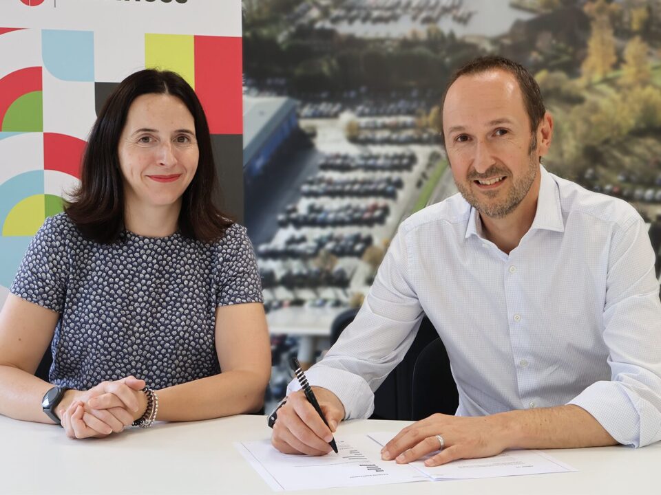 A picture of two people at a table and one is signing a document