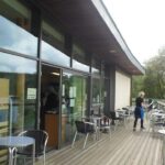 Picture of a cafe with a person organising chairs.