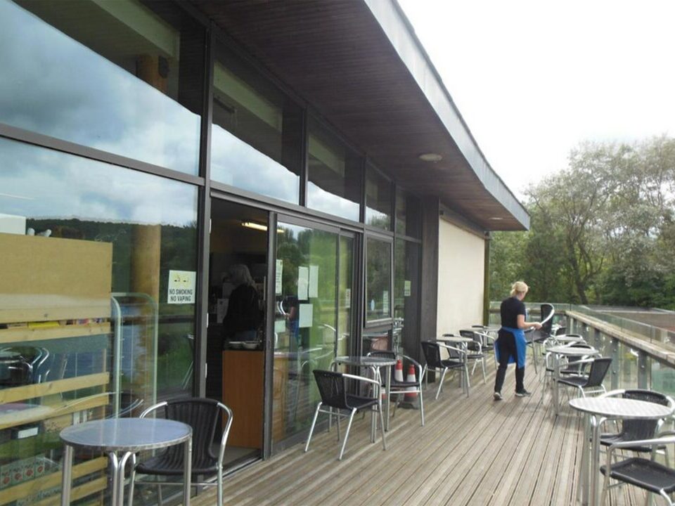 Picture of a cafe with a person organising chairs.