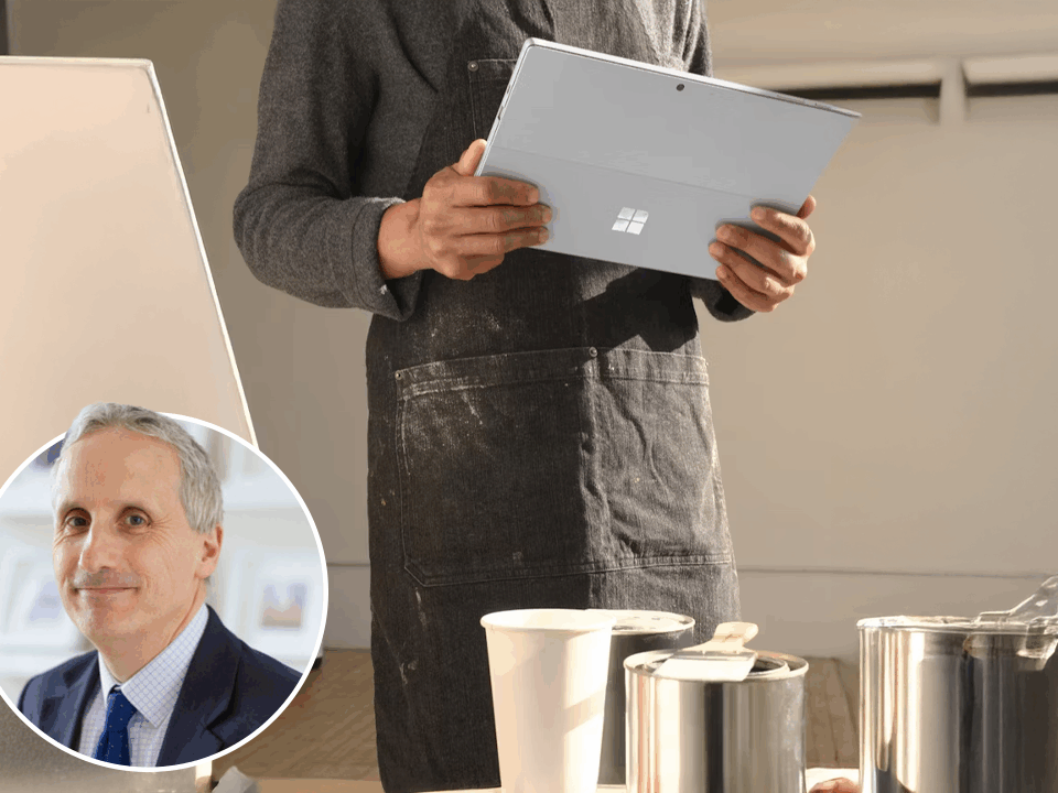 Picture of someone holding a laptop to paint, and a man is at the bottom left of the picture smiling.