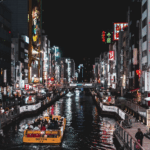 Picture of Japan, City life with shops on either side of a Canal, with a car boat driving ahead.