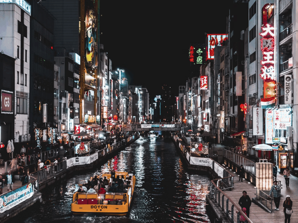 Picture of Japan, City life with shops on either side of a Canal, with a car boat driving ahead.
