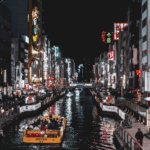 Picture of Japan, City life with shops on either side of a Canal, with a car boat driving ahead.