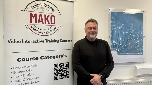 Person standing next to Mako sign, which entails skills like management and business.