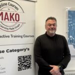 Person standing next to Mako sign, which entails skills like management and business.