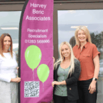 People from Harvey Beric Associates standing next to a banner. Supporting local employers and candidates.