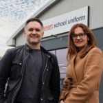 1 person from smart school uniform and another from Staffordshire chambers of commerce stood Infront of smart school uniform building.